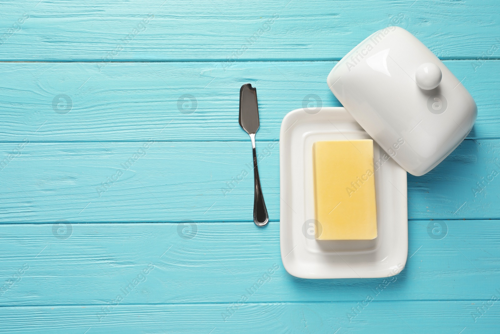 Photo of Dish with fresh butter and knife on wooden background, top view. Space for text