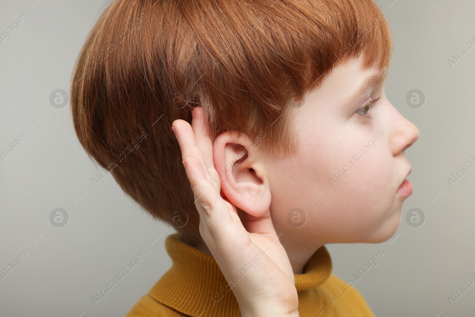 Photo of Little boy with hearing problem on grey background, closeup