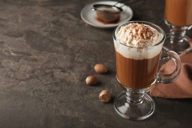 Photo of Hot drink with nutmeg powder on grey table. Space for text