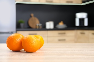 Photo of Fresh oranges on wooden table in kitchen. Space for text
