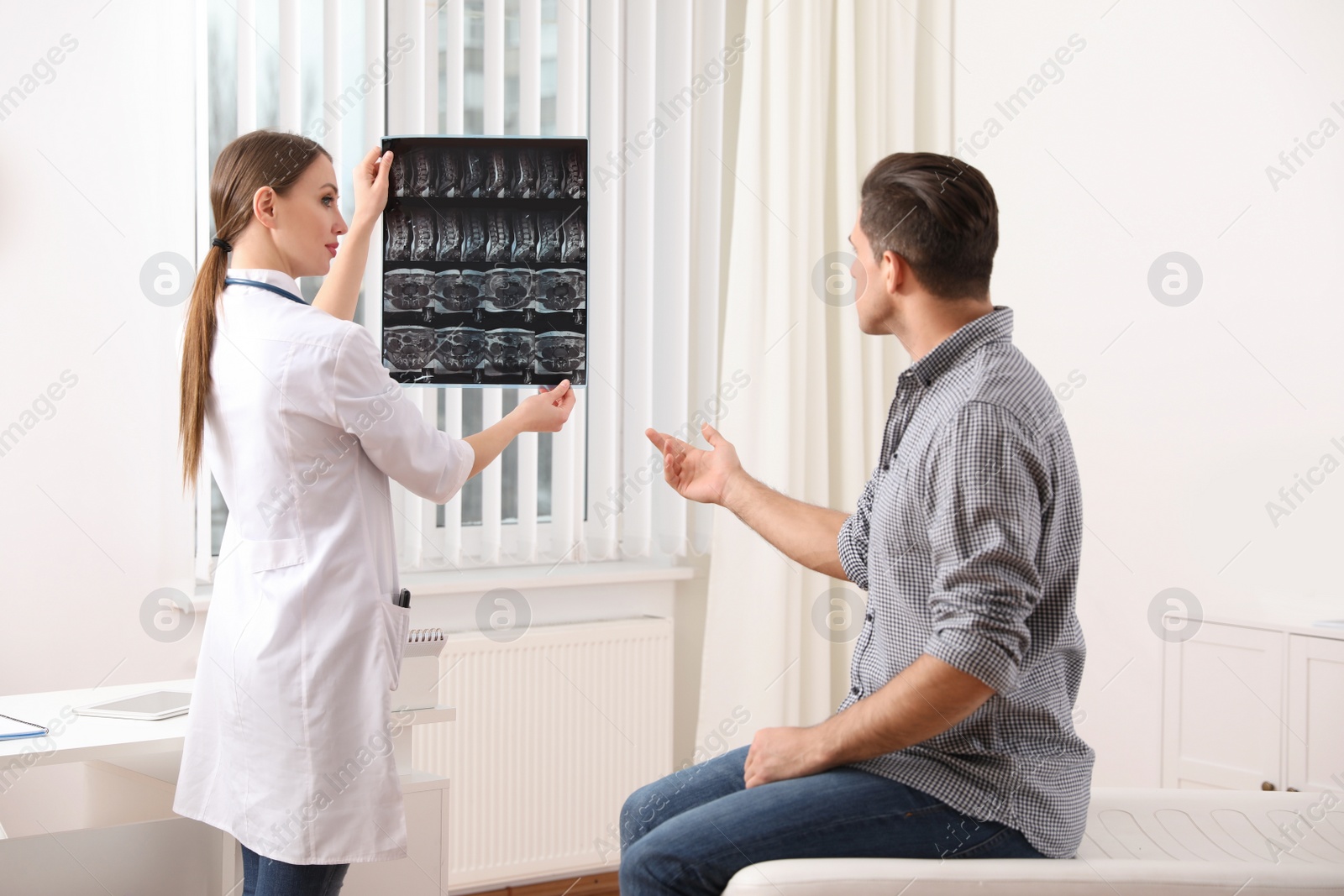 Photo of Orthopedist showing X-ray picture to patient in clinic