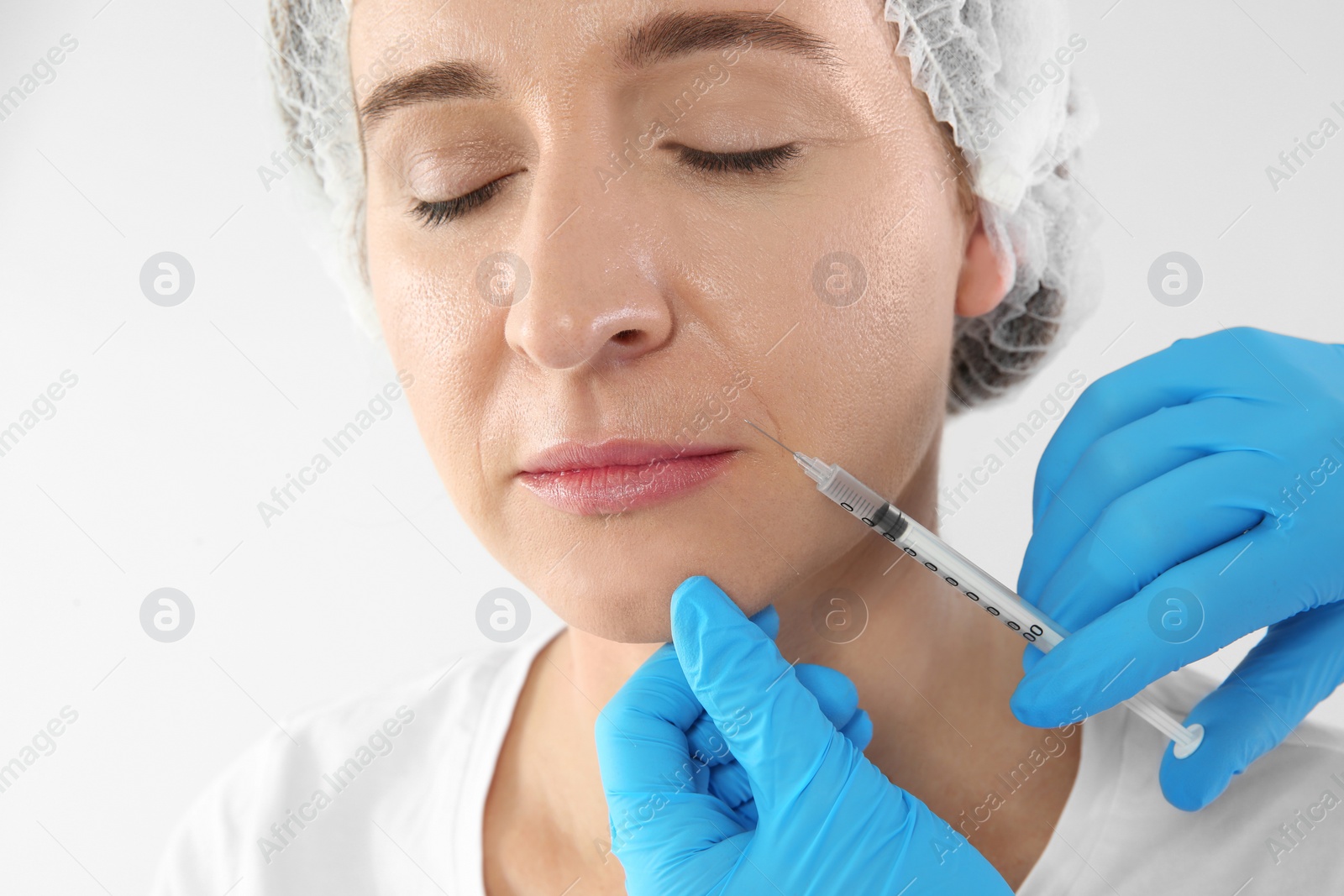 Photo of Mature woman getting facial injection on white background. Cosmetic surgery concept