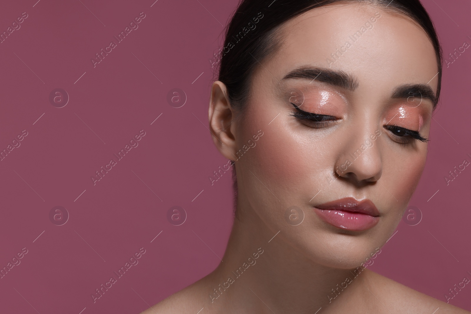 Photo of Portrait of beautiful young woman with perfect makeup on dark pink background. Space for text