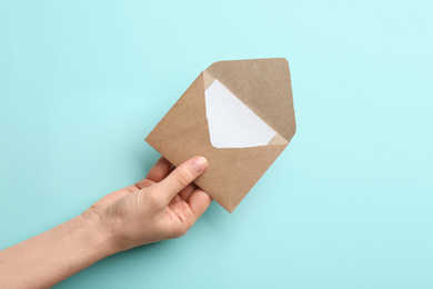 Photo of Woman holding brown paper envelope on light blue background, closeup