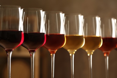 Glasses of different wines against blurred background, closeup. Expensive collection