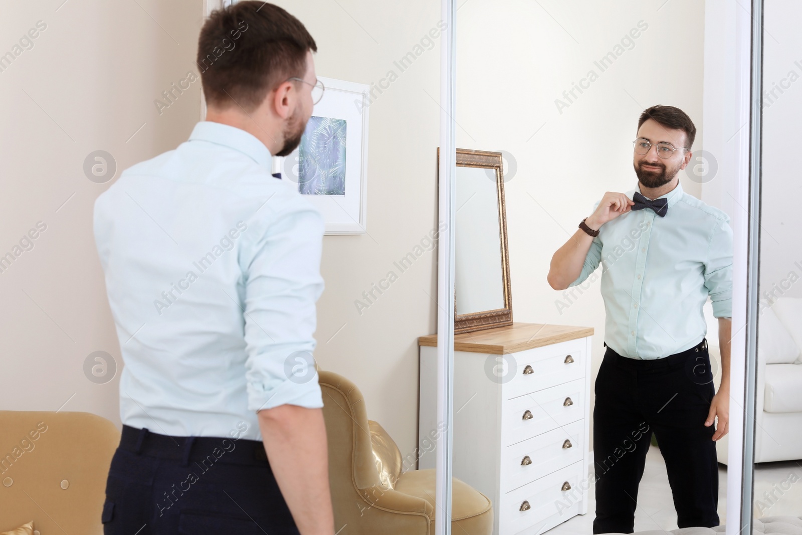 Photo of Young handsome man near mirror in makeup room