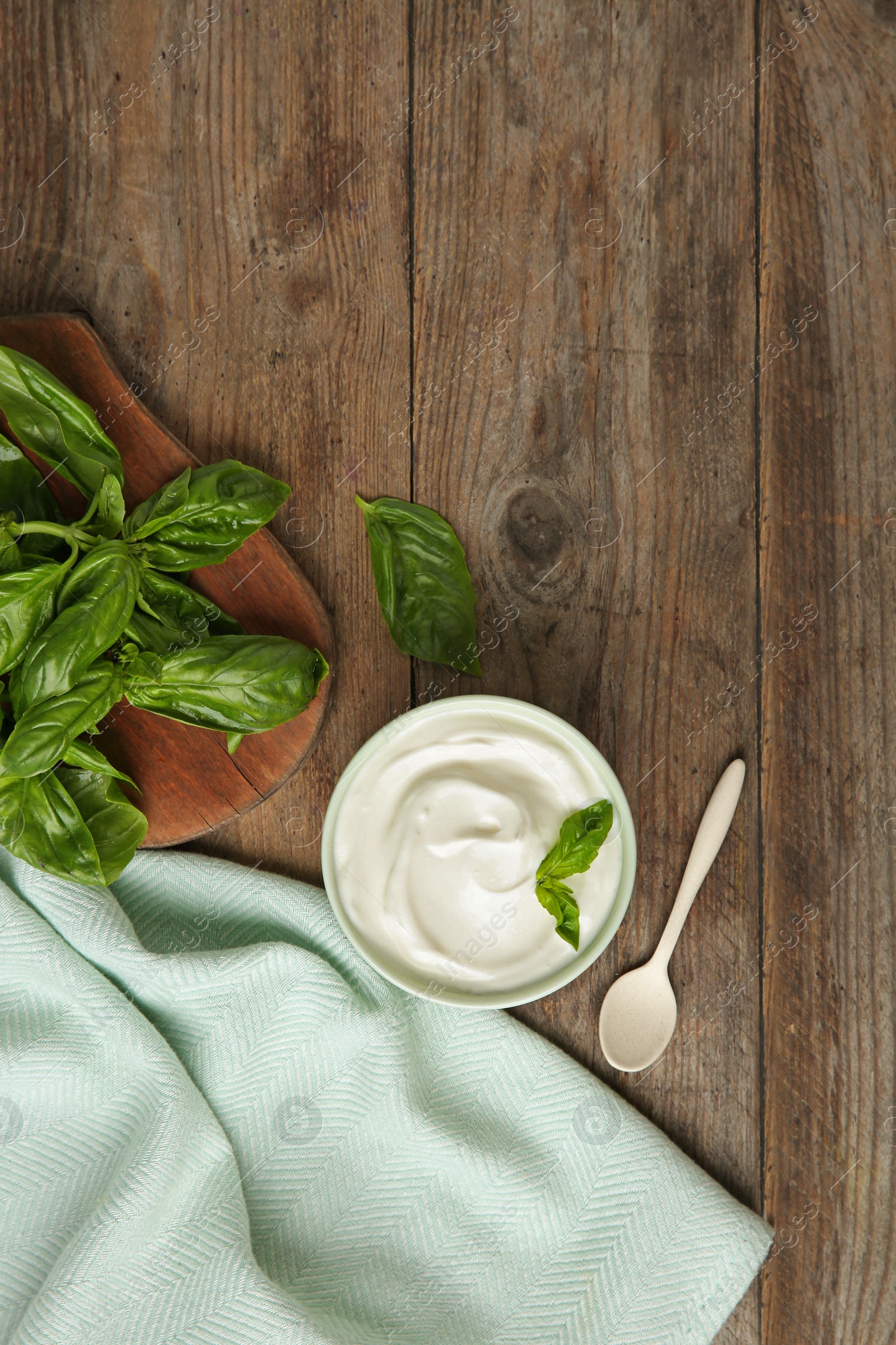 Photo of Flat lay composition with sour cream and basil on wooden table, space for text