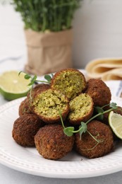 Photo of Delicious falafel balls and microgreens on table