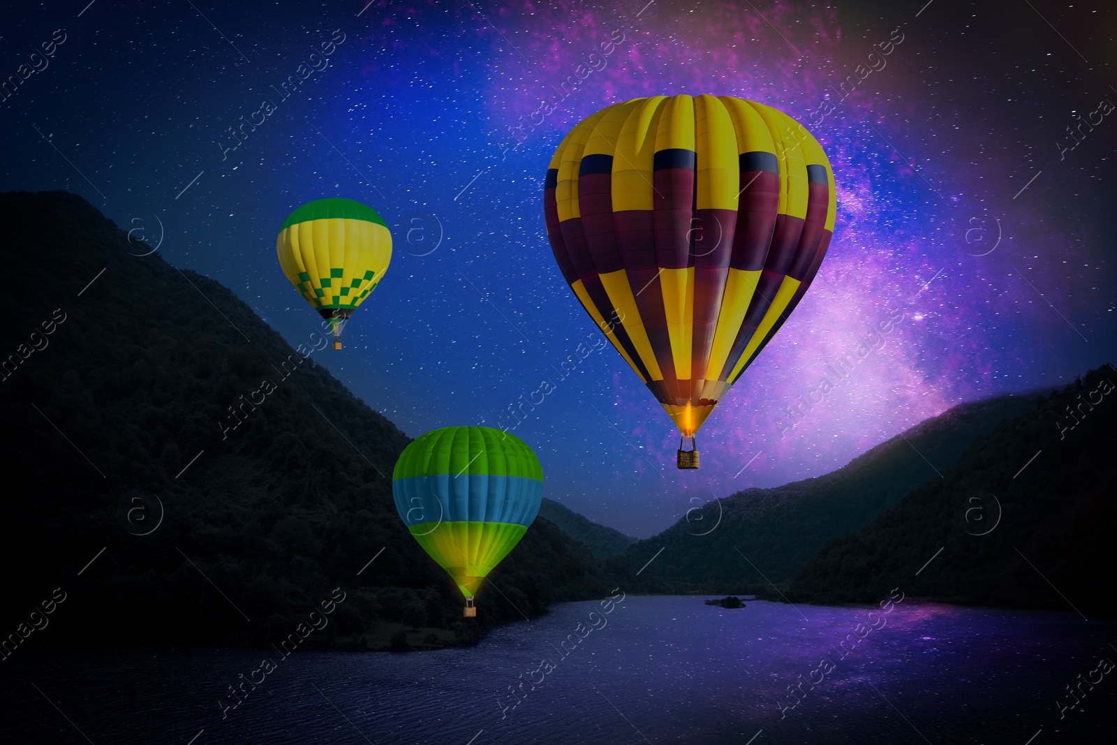 Image of Bright hot air balloons flying over lake at night