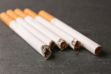 Photo of Many burnt cigarettes on black table, closeup. No smoking concept