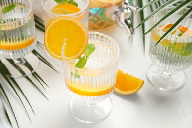 Photo of Delicious refreshing drink with orange and mint on white table