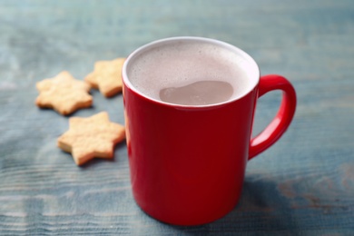 Cup of tasty cocoa and cookies on blue wooden table