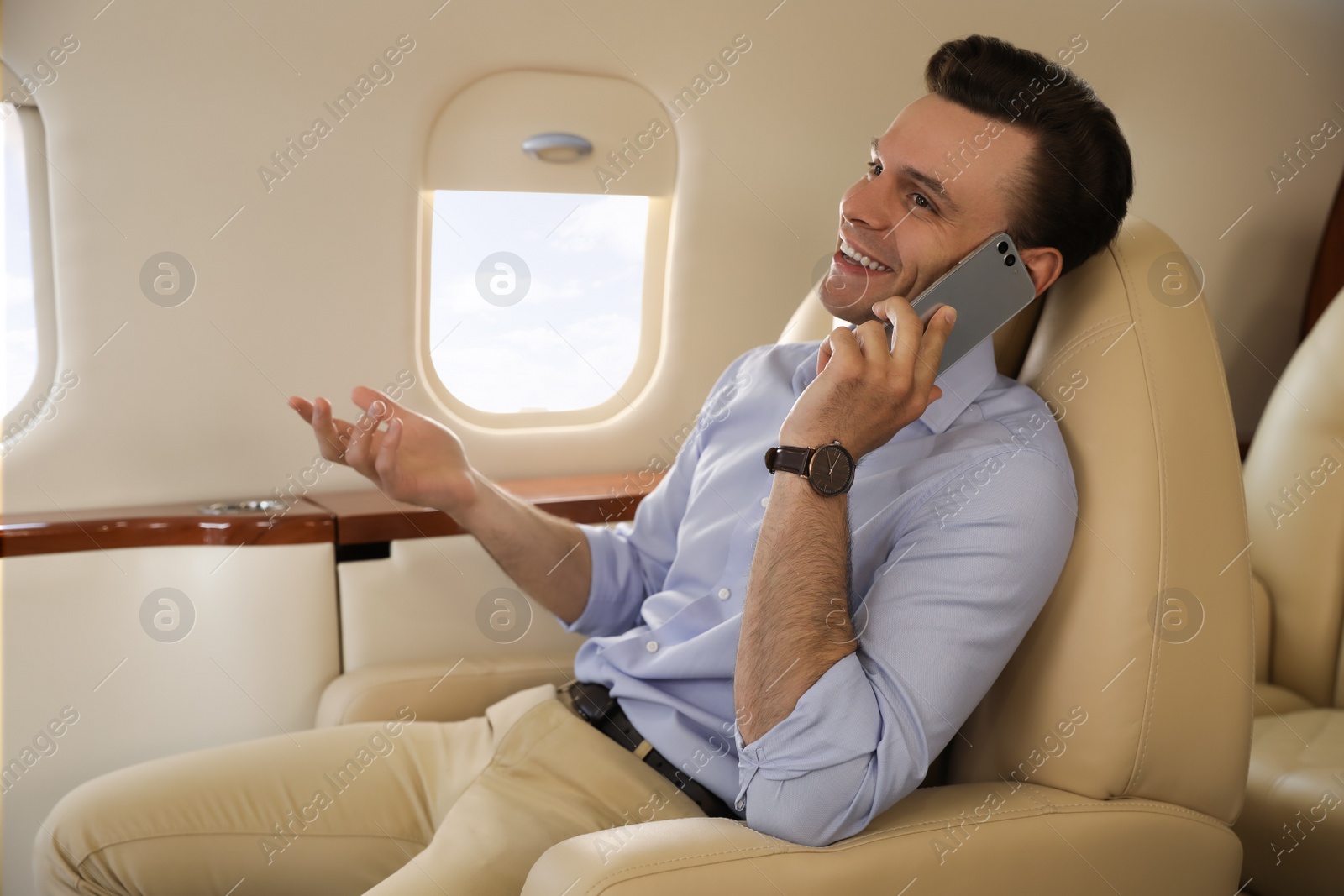 Photo of Businessman talking on mobile phone in airplane during flight