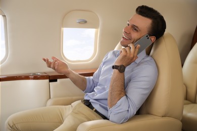 Businessman talking on mobile phone in airplane during flight