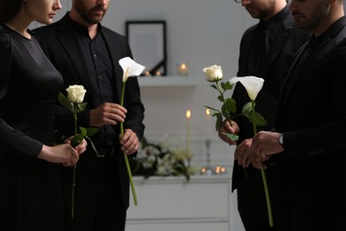 Photo of People with flowers indoors, closeup. Funeral ceremony
