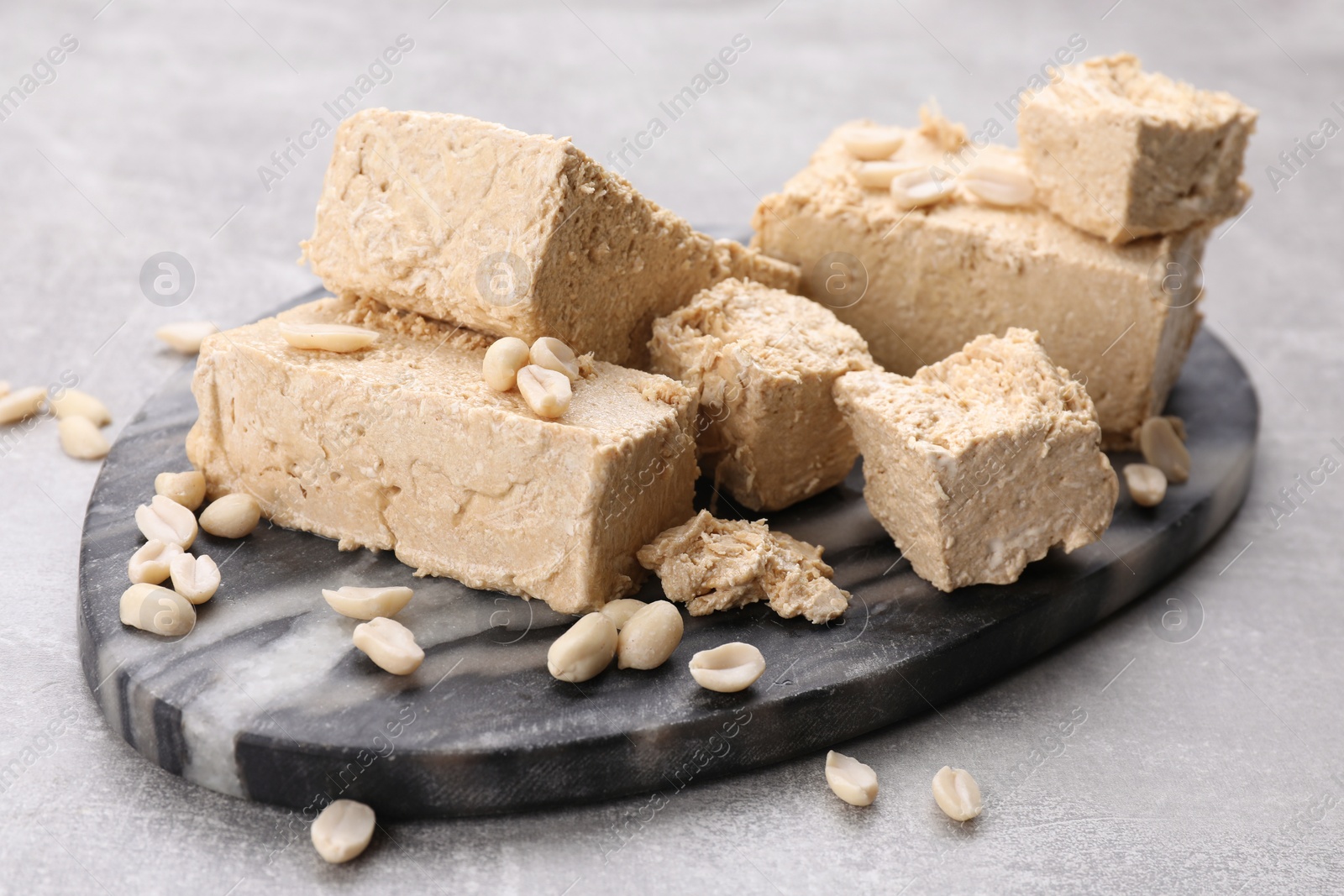 Photo of Pieces of tasty halva on light gray table, closeup