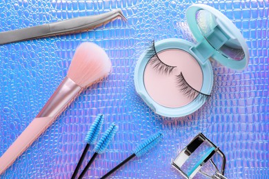 Photo of Flat lay composition with false eyelashes and cosmetic products on texture colorful background