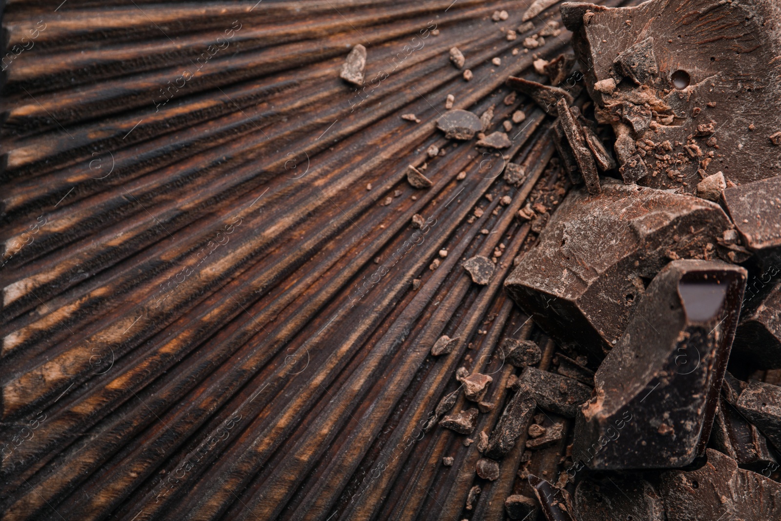 Photo of Pieces of dark chocolate on wooden board, flat lay. Space for text