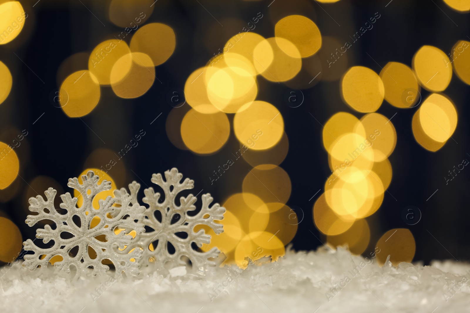 Photo of Beautiful decorative snowflakes against blurred festive lights, space for text