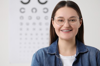 Photo of Young woman with glasses against vision test chart