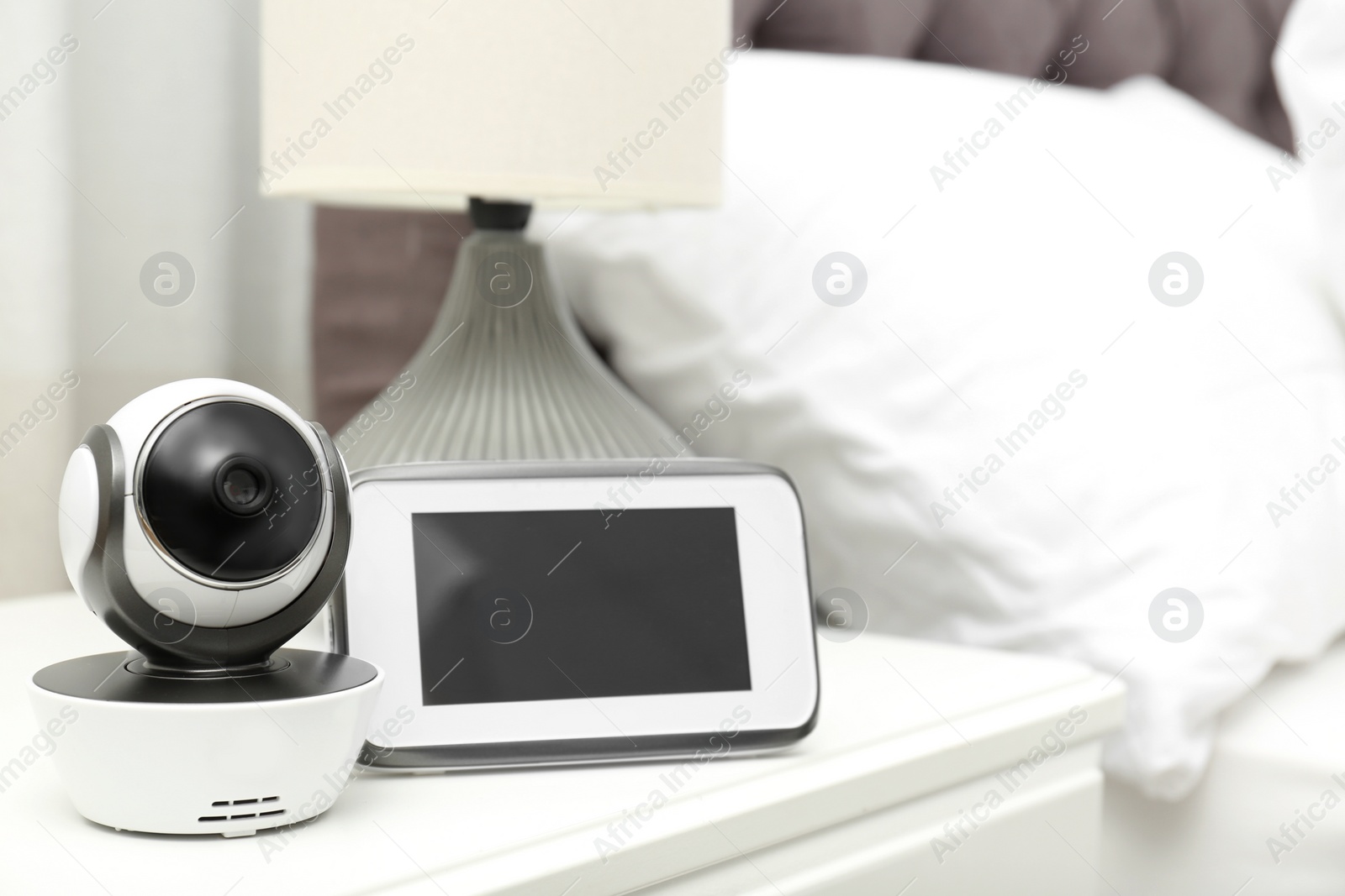 Photo of Baby monitor with camera on table in bedroom, space for text. Video nanny