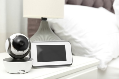 Baby monitor with camera on table in bedroom, space for text. Video nanny