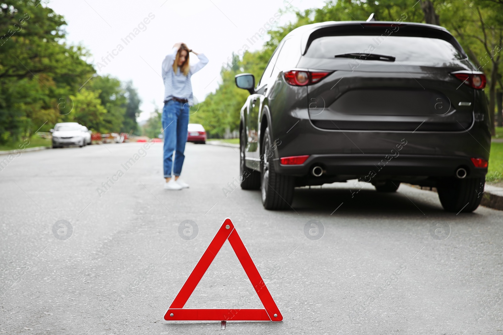 Photo of Emergency stop sign and woman near broken car on background