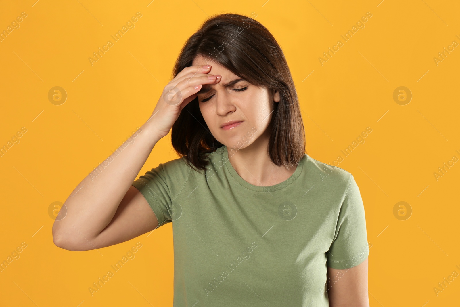 Photo of Young woman suffering from migraine on yellow background