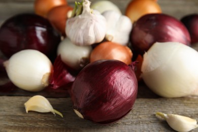 Photo of Fresh onion bulbs and garlic on wooden table, closeup