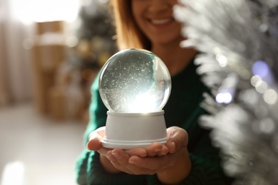 Happy woman at home, focus on hands with snow globe