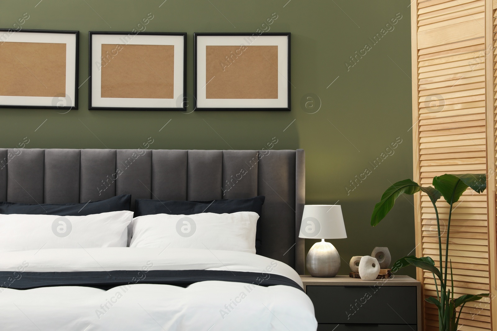 Photo of Comfortable bed, nightstand, lamp and houseplant in stylish room. Interior design