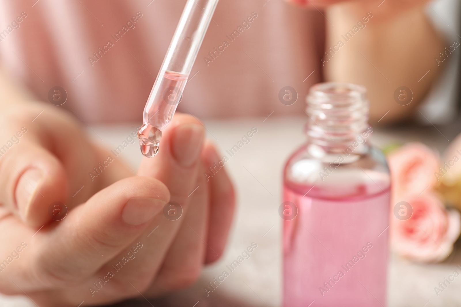 Photo of Woman dripping rose essential oil on finger, closeup. Space for text