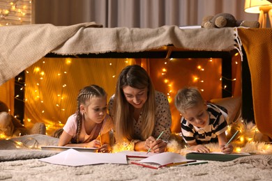 Mother and her children drawing in play tent at home