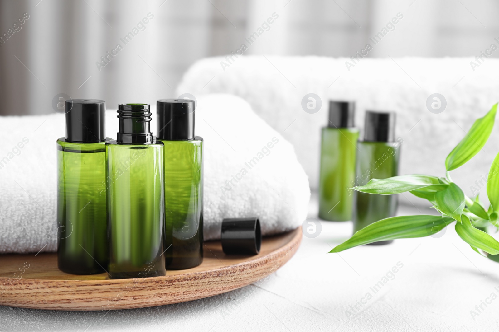 Photo of Composition with mini bottles of cosmetic products and towel on white table