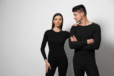 Couple wearing thermal underwear on light grey background. Space for text