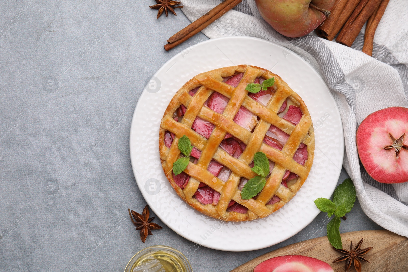 Photo of Delicious apple pie with mint and ingredients on grey table, flat lay. Space for text