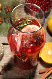 Photo of Glass bottle of aromatic punch drink on wooden table, closeup