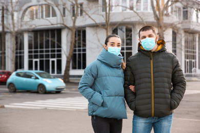 Photo of Couple wearing disposable masks outdoors. Dangerous virus