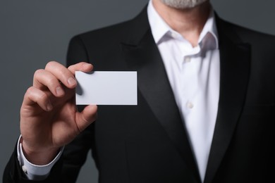 Man holding blank business card on grey background, closeup