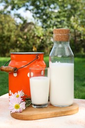 Photo of Tasty fresh milk on color textured table outdoors