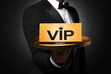Photo of Man holding tray with VIP sign on black background, closeup