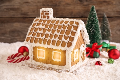 Photo of Beautiful gingerbread house decorated with icing and Christmas balls on snow