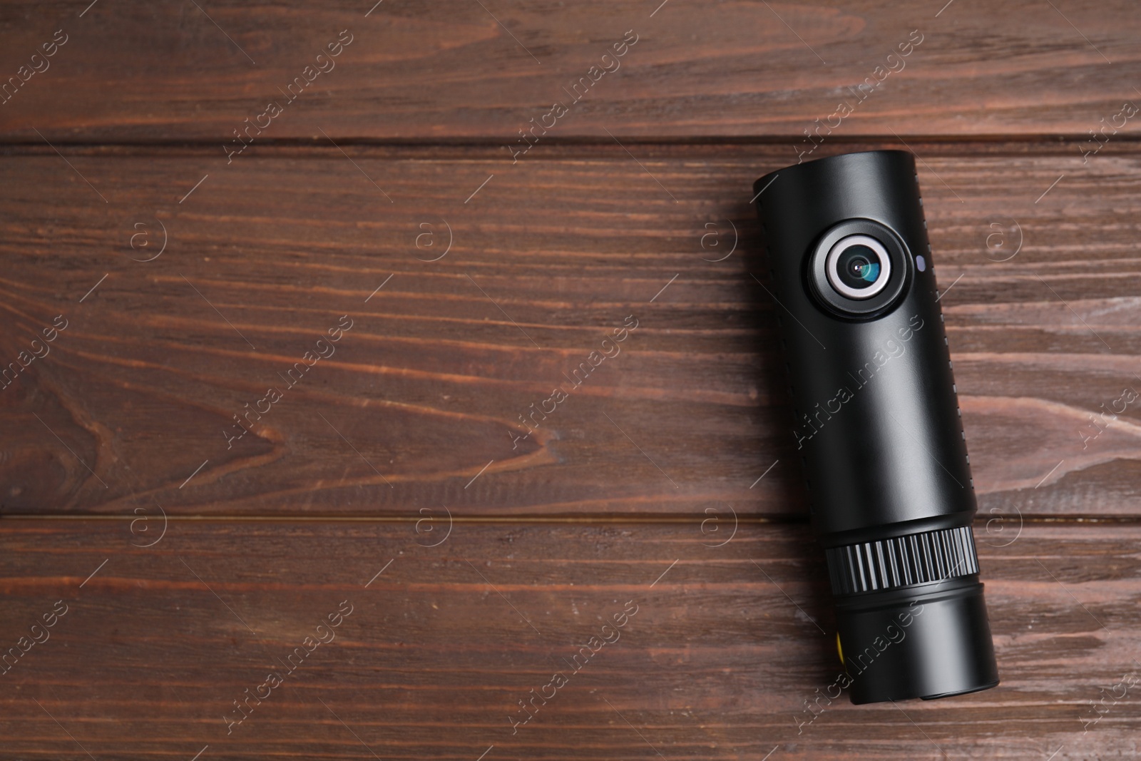 Photo of Black modern car camera on wooden table, top view. Space for text