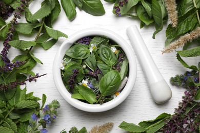 Photo of Flat lay composition with mortar and different healing herbs on white wooden table