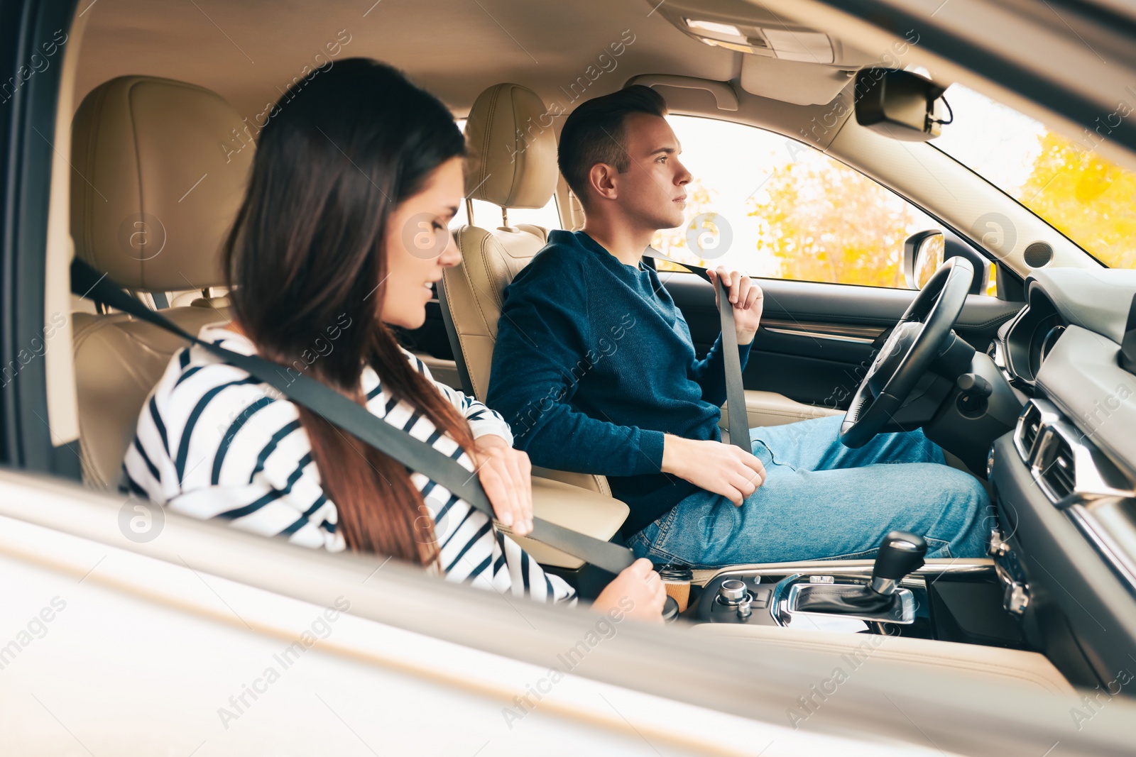 Photo of Happy young couple fastening seat belts in car