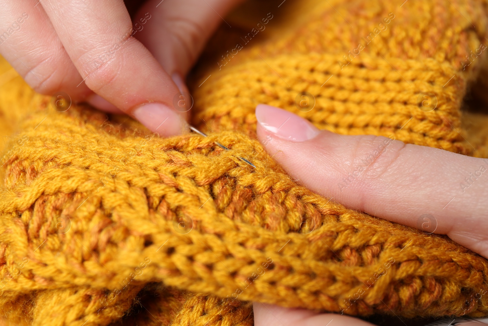 Photo of Woman sewing sweater with needle, closeup view