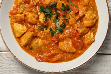 Photo of Delicious chicken curry on wooden table, top view