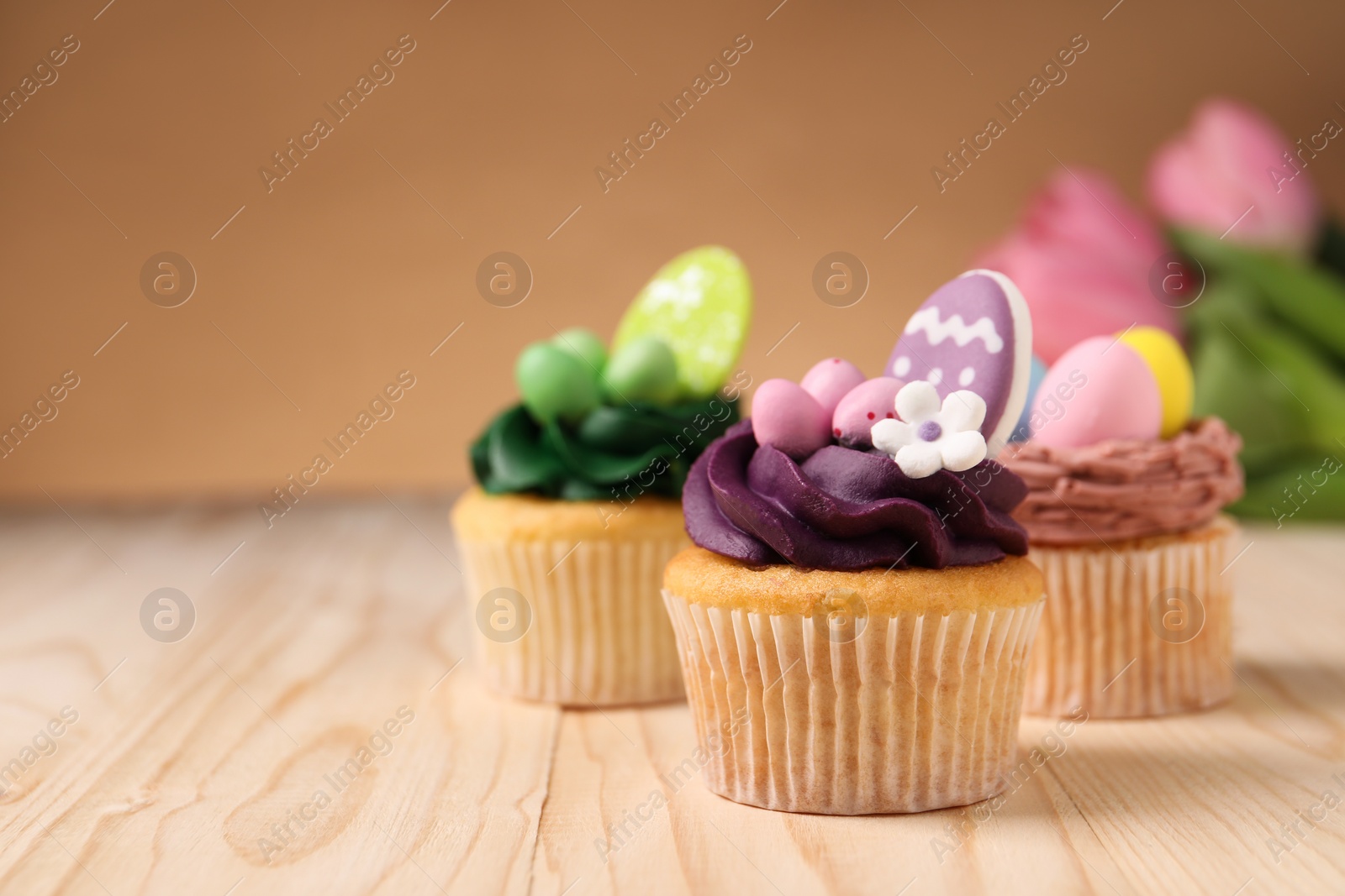 Photo of Tasty cupcakes with Easter decor on wooden table, space for text