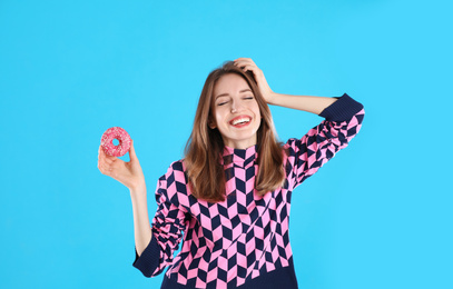 Photo of Beautiful young woman with donut on light blue background