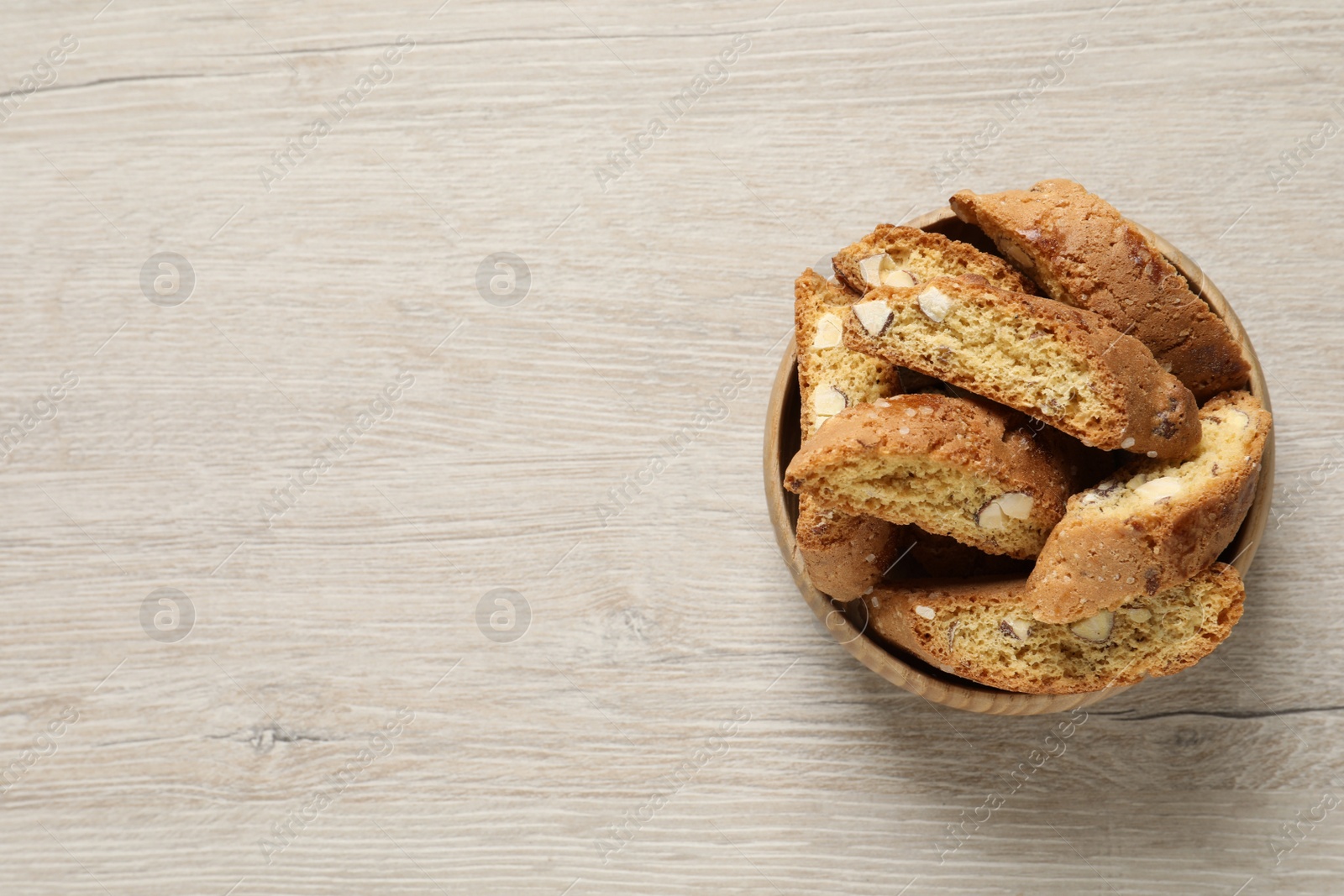 Photo of Traditional Italian almond biscuits (Cantucci) on white wooden table, top view. Space for text